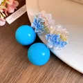 Detailed view of iridescent resin flower earrings with bright blue spherical studs - Floral Round Bead Shape / Blue