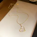 Close-up of elegant gold-toned heart pendant necklace with shimmering zircon stones. - Gold