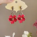 Detailed close-up view of vibrant red enamel flower dangle earrings on ginkgo leaf card - Silver Earring Post - Red