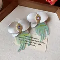 Vue macro détaillée d'élégantes boucles d'oreilles fleurs en résine avec cristaux violets. - Fleur Hirondelle (HE31585) / Or-Blanc-Vert