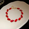Detailed macro view of teardrop-shaped red zircon stones on a gold-plated luxury bracelet - Gold-Red