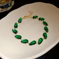 Close-up detail of emerald green teardrop cubic zirconia on a luxury gold-plated bracelet - Gold-Green