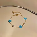 Detalle de cerca de una pulsera de acero inoxidable con flores azules y circonitas - Dorado-Azul