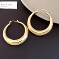 Detailed view of shiny gold-toned chunky tapered hoop earrings on dark background - Bright Gold