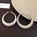 Close-up of chunky silver-toned metal hoop earrings with high-polish finish - Bright Silver