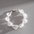 Nahaufnahme der Textur eines eleganten weißen Glasperlen- und Imitationsperlenarmbands - Armband / Weiß