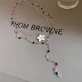 Close-up detail of vintage style crystal beaded necklace featuring white flower pendant - Silver