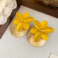 Detailed macro shot of yellow oil-drop flower earrings featuring golden pleated textures - Yellow