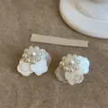 Primer plano de elegantes pendientes de perlas blancas de estilo francés con pétalos de flores. - Perno de plata-Blanco