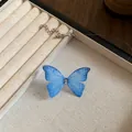 Close-up detail of a blue translucent butterfly pendant on a transparent choker necklace - Blue