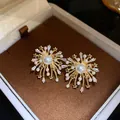 Close-up detail of starburst firework stud earrings with pearls and sparkling zircons - Steel Pin Style / Gold