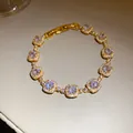 Détail d'un bracelet plaqué or 18 carats avec breloques carrées en zircons étincelants - Or
