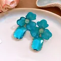 Close-up detail of blue acrylic flower earrings with faceted rectangular gem drops - Blue
