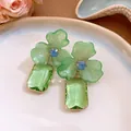 Close-up detail of elegant green acrylic floral earrings with rectangle crystal drops - Green