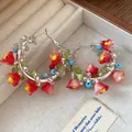 Detailed close-up of colorful glass beaded hoop earrings featuring delicate red flower charms - Flower Beaded Style (HE32794) / Silver-Red