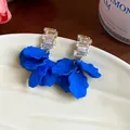 Primer plano de pendientes de pétalos de acrílico azul Klein con circonitas - Dorado-Azul