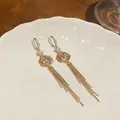 Detail view of 18k gold plated tulip earrings with zircon stones and long tassels - Hook Style / Gold+White