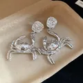 Detailed close-up of silver-toned crab dangle earrings with a unique textured metal finish - Crab Design / Silver
