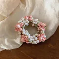 Close-up detail of a sweet pearl and pink fabric flower hair scrunchie accessory - Pink