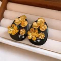 Macro shot of vintage black resin earrings with intricate golden flower motifs in a beige tray - Silver Earring Post Style / Gold-Black