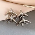 Macro view of unique silver geometric earrings featuring pearl and sparkling crystal details. - Geometric Bird Shape / Silver