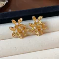 Macro detail of elegant gold floral stud earrings featuring delicate pearl centers - Gold & White (925 Silver Post)