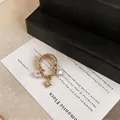 Detail view of gold-tone double-layer ear cuff with star pendant and zircons charms - Single Piece / Gold