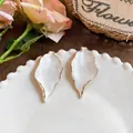 Vintage gold leaf white textured earrings elegantly displayed on a white plate backdrop - White
