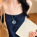 Detail shot of a summer blue cord necklace featuring a circular shell resin pendant - Necklace / Blue (Glass Pendant)