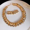Close-up of vintage gold chunky pleated necklace and earrings set on white plate - Gold