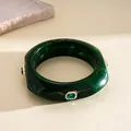 Macro shot of a dark green marbled resin bangle with emerald-cut crystal details - Green