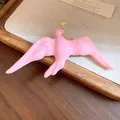 Macro detail of the pink enamel swallow brooch with elegant gold accents - Pink