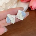 Dettaglio ravvicinato di orecchini a lobo minimalisti a forma di rombo in vetro tricolore. - Argento-Rosa-Blu
