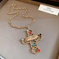 Close-up of a vintage gold cross necklace with a lip charm and colorful resin stones - Lip Cross Necklace / Gold