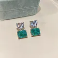 Detail view of heart and square emerald-green stud earrings on a velvet box background - Heart and Square (HE32170) / Silver-Green