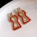 Close-up of geometric red enamel drop earrings with sparkling crystal studs in gold - Red