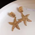 Detailed macro view of vintage gold starfish drop earrings with a granular texture - Gold