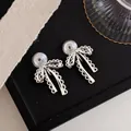 Detailed shot of silver lace bow clip-on earrings with mosquito coil backs for non-pierced ears - Clip-On Earrings / Silver