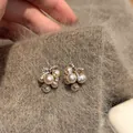 Macro detail of pearl cluster stud earrings with zircon bow on soft fabric background - Brown