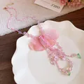 Vue détaillée du collier de perles roses avec fleur en tissu et glands sur assiette blanche. - Collier / Rose