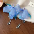 Detailed view of blue chiffon flower earrings with shimmering crystal water drop charms - Blue