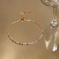 Detail view of a gold adjustable bracelet featuring a row of colorful square zircons. - Gold
