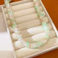 Gros plan d'un collier en perles de verre vertes et champagne en boîte. - Blanc-Vert