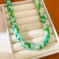 Gros plan d'un collier torsadé orné de perles de verre colorées vertes et bleues. - Vert-Café