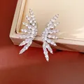 Close-up of wing-shaped ear clips with sparkling white cubic zirconia stones. - Silver