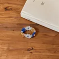 Detail view of a colorful handmade flower beaded bracelet on a wooden table. - Ring / Blue-Brown