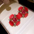 Dettaglio di orecchini vintage con pietra occhio di gatto rossa e cristalli scintillanti - Rosa Rosso