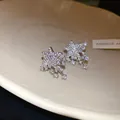 Detail view of silver star stud earrings with brilliant dangling crystals on white dish - Meteor Style (HE33720) / Silver