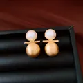 Dettaglio di orecchini a lobo geometrici in perla placcati oro 18k su vassoio nero - Oro