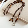 Close-up of vintage ethnic style leather rope waist chain with wooden beads on book - Brown